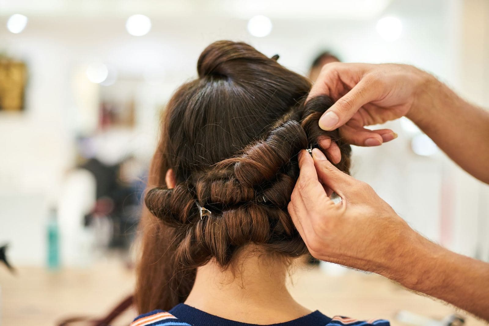Editorial stock: long chestnut hair being placed and pinned. Not client work.
